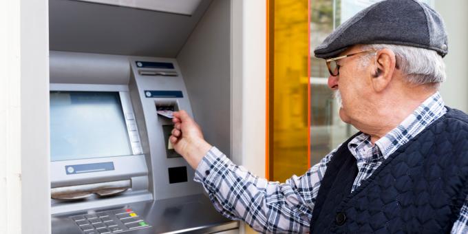 Bild: älterer Mann mit Bankkarte vor Bankautomat für Digital-Kompass Webinar Finanzen im Ruhestand