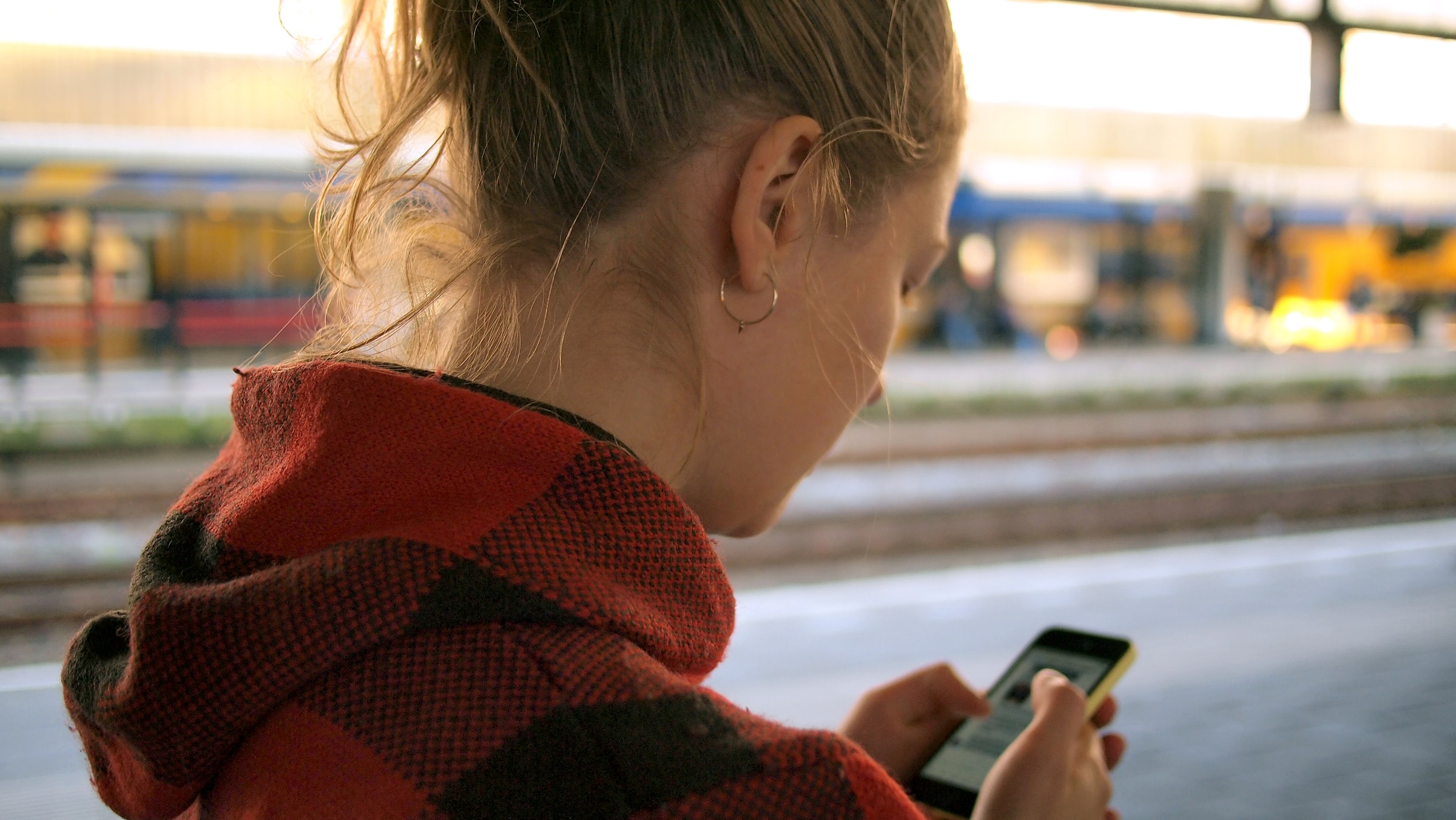 Coronavirus in Deutschland: Eine Frau steht an einem verwaisten Bahnhof und schaut auf ihr Handy. Was bei Corona-Apps bei Datenschutz und ITSicherheit zu beachten ist. ihr Handy