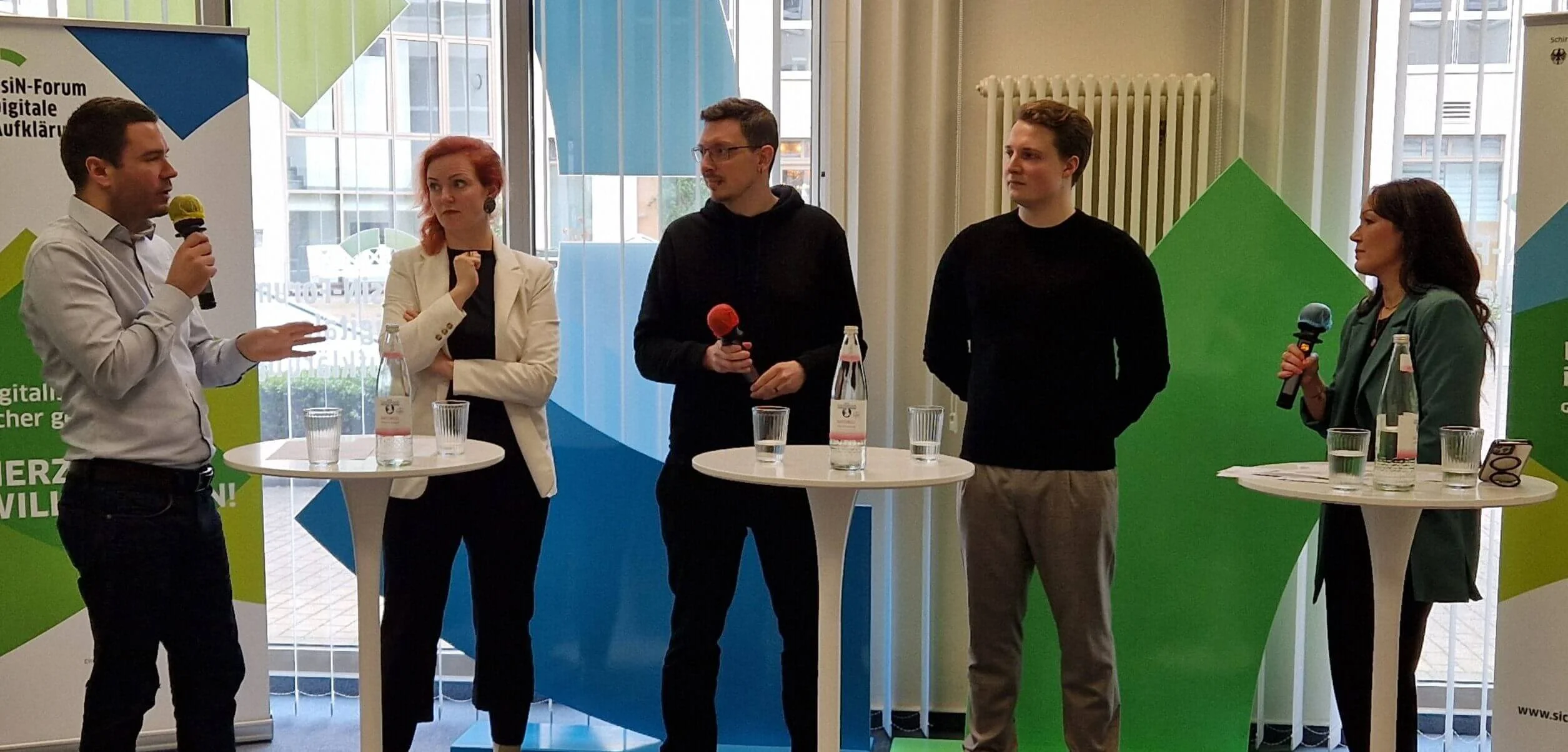 Die Teilnehmenden des Panels stehen nebeneinander. Pierre du Bois spricht in ein Mikrofon hinein und adressiert Lukas Hoof, Michaela Schröder, Martin Meingast und Isabelle Rosière.